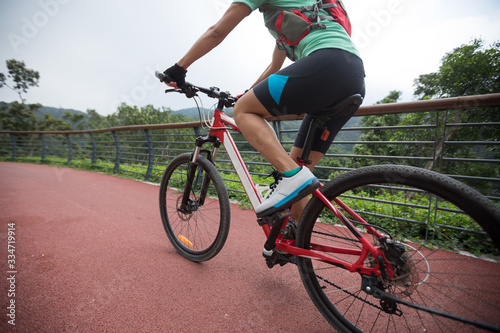 Woman cyclist riding mountain bike on forest trail