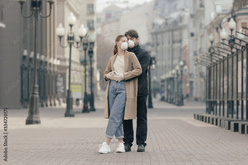Young couple in love in the empty streets in medical masks. Virus protection concept