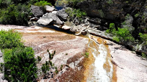 Aerial shot of flowing water at Conceicao dos gatos waterfall, Chapada Diamantina, Bahia, Brazil. Drone moving forward and following water flow.