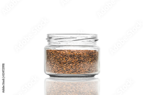 glass jar with flaxseeds on a white background, selective focusing