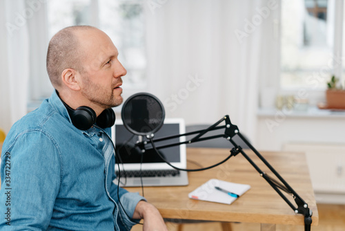 Man seated at a desk alongside podcast equipment