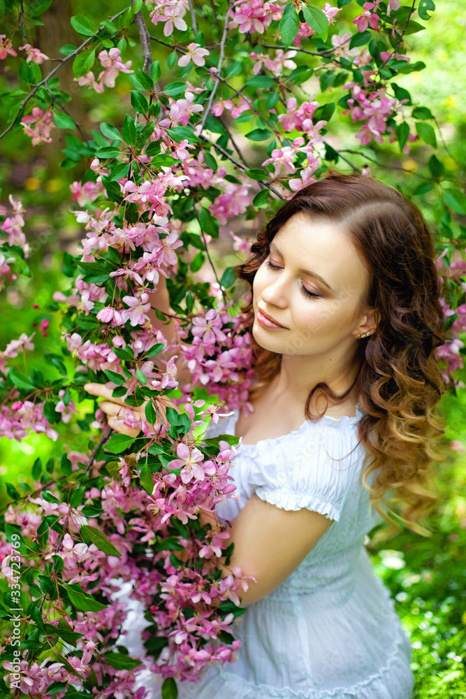 Happy young girl enjoy peach blossom. Spring walk in the blooming garden Happy young girl enjoy peach blossom. Spring walk in the blooming garden