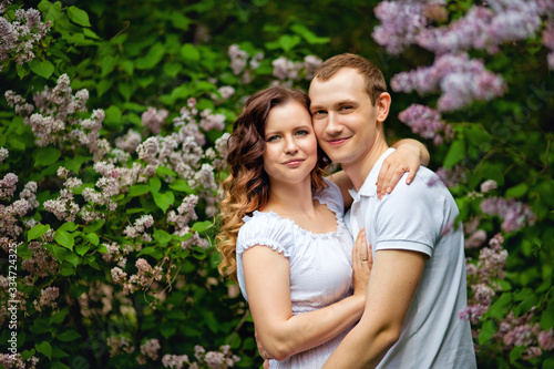 Romantic holidays for a guy and a girl in a spring park. Meeting a young couple in a lilac garden. Photo session in nature.
