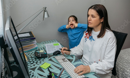 Foto Woman telecommuting making a video conference with her daughter grimacing behind