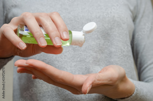 Women's hands using green antibacterial hand gel close up