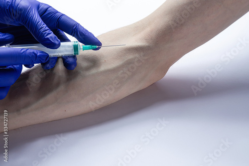 the doctor takes a blood test from a vein with a syringe from a patient