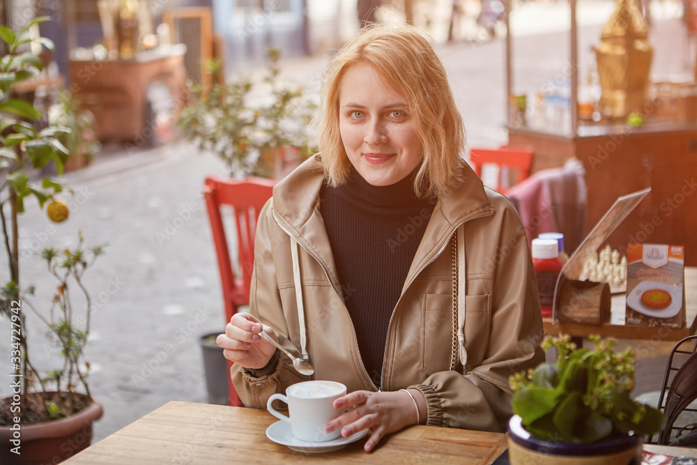 Young white woman is relaxing in a street cafe.