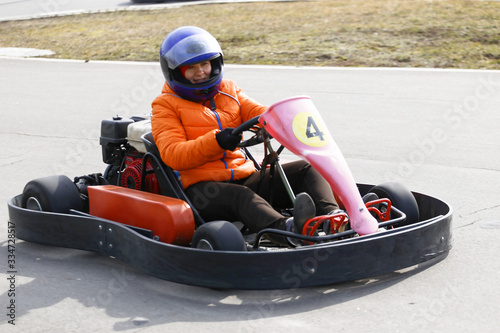 girl is driving Go-kart car with speed in a playground racing track.