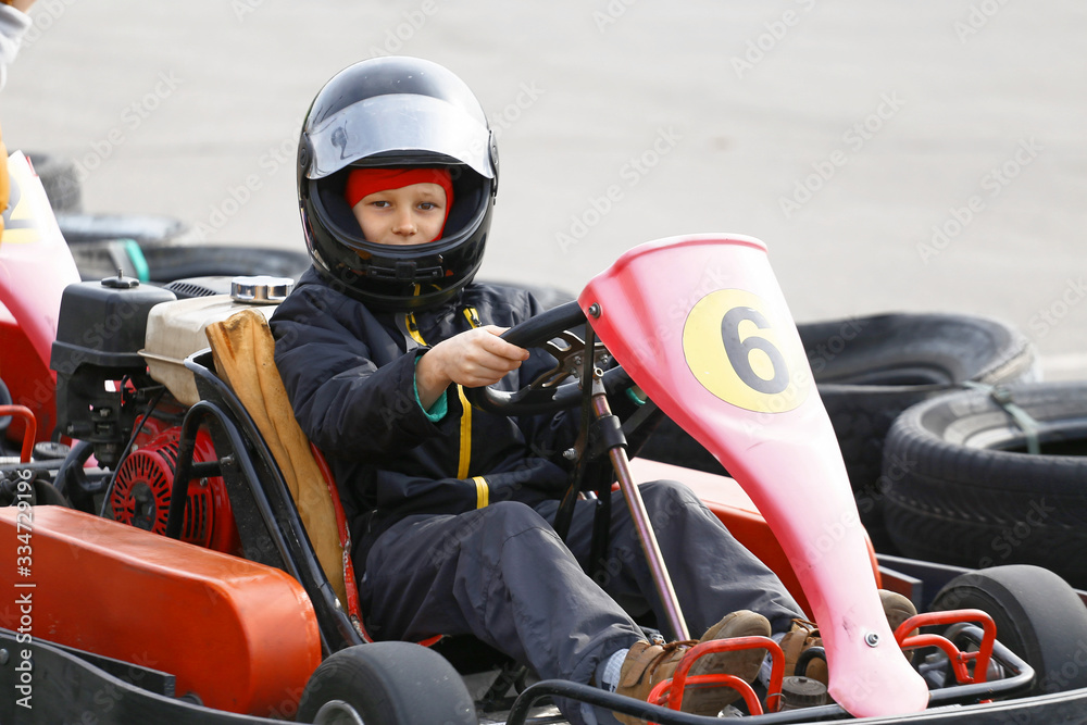 boy is driving Go-kart car with speed in a playground racing track.