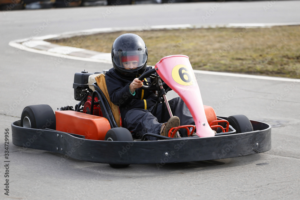 boy is driving Go-kart car with speed in a playground racing track.