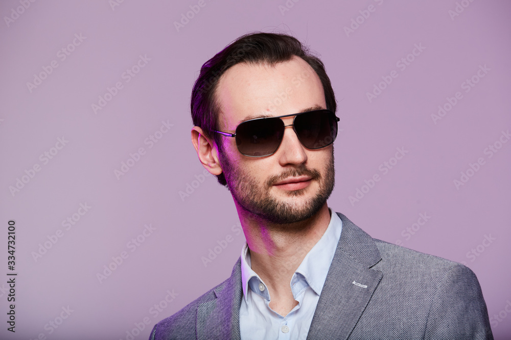 Elegant young handsome man in sunglassesand in stylish gray jacket. Studio fashion portrait. Elegant young handsome man in sunglassesand in stylish gray jacket. Studio fashion portrait.