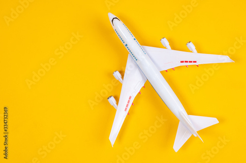 Airliner on a yellow background. Miniature model of an airplane. Aircraft model top view. Airliner for civilian flights. Modern airplane top view. Place for an inscription. Aviation. Toy plane