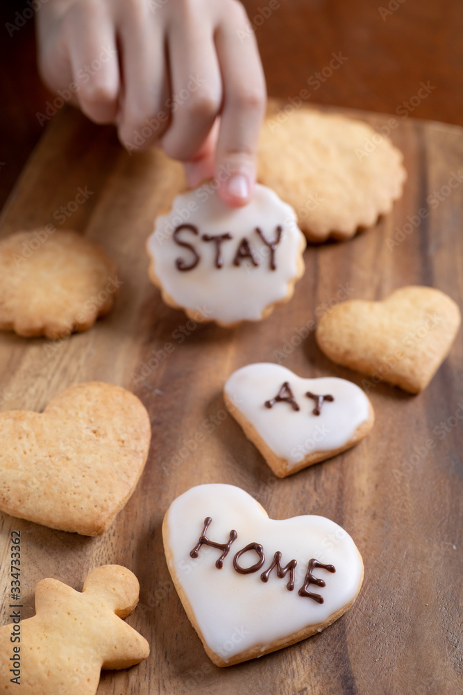 stay at homeと書かれたアイシングクッキーを持つ子供 stay at homeと書かれたアイシングクッキーを持つ子供