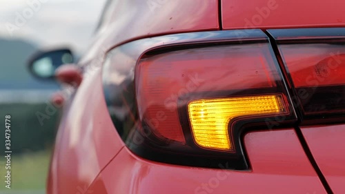 Flashing rear hazard warning lights on a car after a road accident during the day with blurred background
