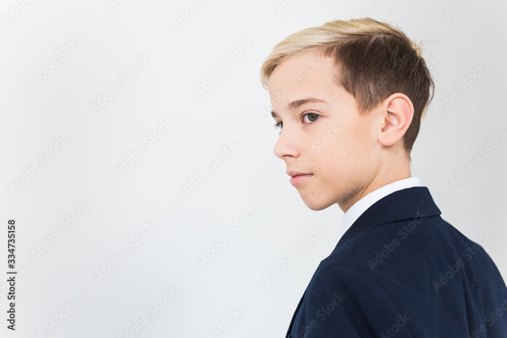 Portrait of stylish school boy teenager in white shirt and jacket against white background.