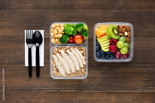 Top view of wholesome nutrient rich food set in take away boxes with spoon and fork on wood table ready to eat photo