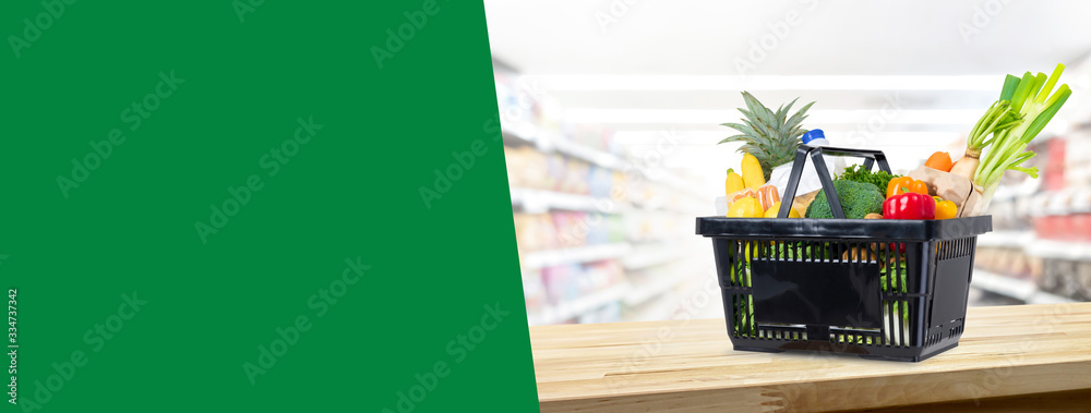Φωτογραφία Shopping basket full of groceries on wood counter in supermarket background bann