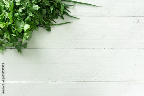 Set of greens for salad on a white wooden background. Place for text.