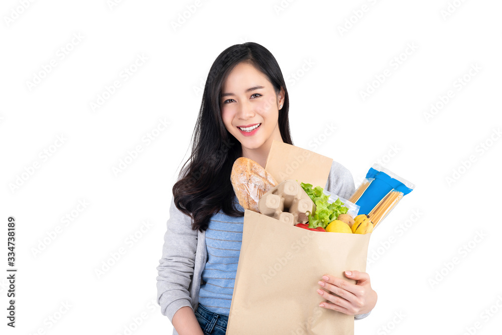 Beautiful smiling Asian woman holding paper shopping bag full of food and groceries isolated on white background Beautiful smiling Asian woman holding paper shopping bag full of food and groceries isolated on white background