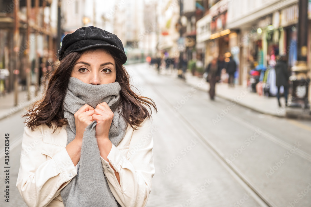 Young beautiful woman covering face with woolen scarf.