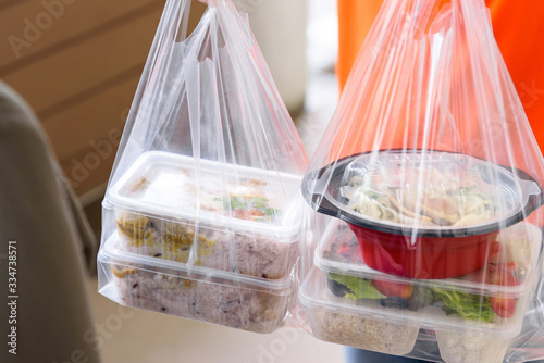 Foto Asian food boxes in plastic bags delivered to customer at home by delivery man