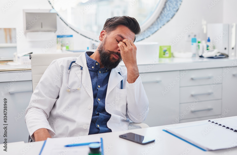 The tired doctor is sitting at the desk The tired doctor is sitting at the desk
