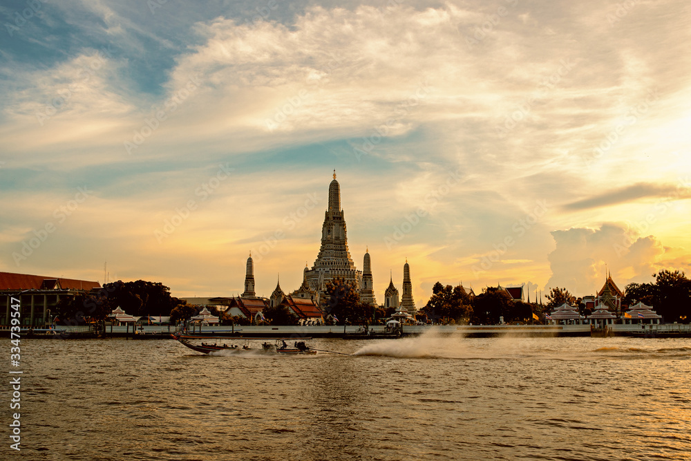 boat sailing in the middle of the Chao Phraya River and Wat Arun, Bangkok