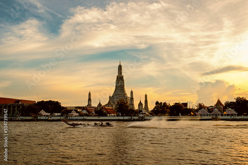 boat sailing in the middle of the Chao Phraya River and Wat Arun, Bangkok © anake