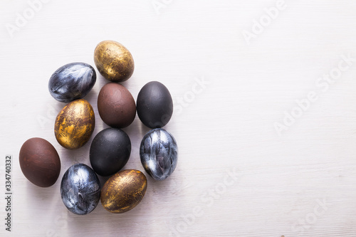 Holidays, traditions and Easter concept - Dark stylish easter eggs on white wooden background with copyspace.