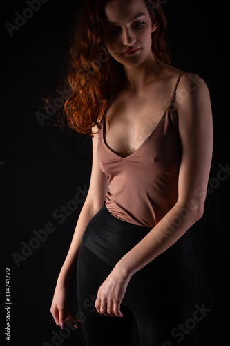 Portrait of a young curly girl in a dark studio