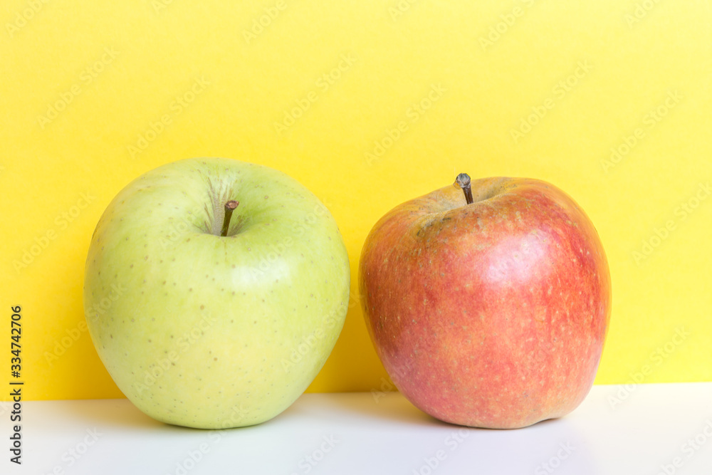 Bright red and green apples on yellow background and white table. Bright red and green apples on yellow background and white table.