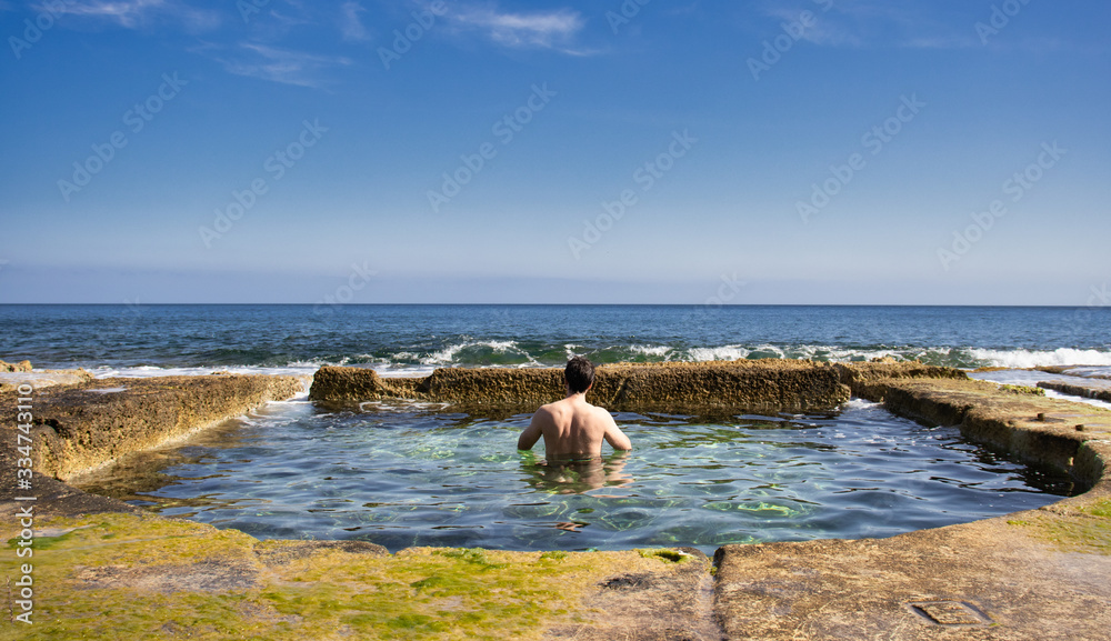 Young man enjoying a natural swimmingpool from sea water, enjoying open water space and warm calm water. with sea view Young man enjoying a natural swimmingpool from sea water, enjoying open water space and warm calm water. with sea view
