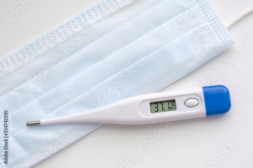 Thermometer with temperature numbers 37.1 on a medical mask in blue on a white background. Coronavirus Precautions Mask Protection.