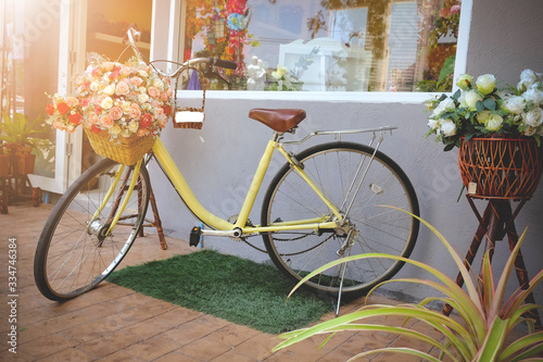 vintage Bicycle with basket full rose flower next to a modern cafe