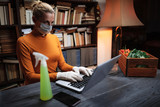 Woman with protective mask from viruses and pathogens using laptop at home, ordering food, groceries, supplies over the internet.