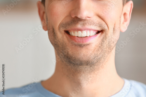 Handsome young man with healthy teeth at home, closeup