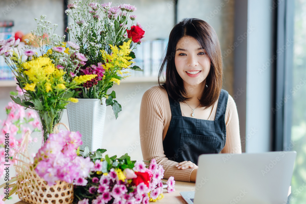 Beautiful Asian woman receive orders from internet in flower shop.