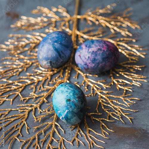  Easter holiday. Easter eggs on a golden branch. Blue background. Close-up.