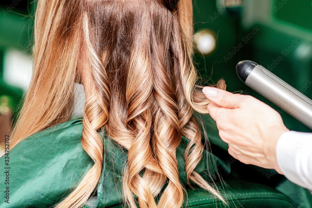 Fototapeta premium Hairdresser twists hair.