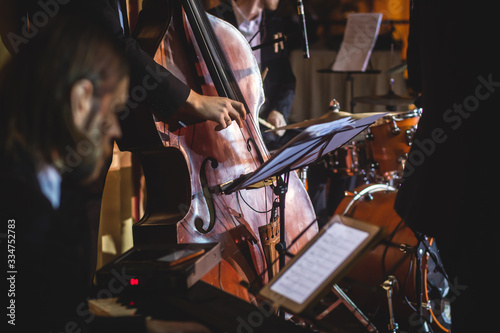 Concert view of a contrabass violoncello player with vocalist and musical during jazz orchestra band performing music  violoncellist cello player on the stage