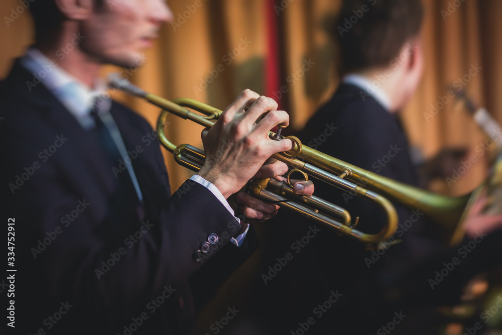 Obraz premium Concert view of a male trumpeter, professional trumpet player with vocalist and musical during jazz band performing music