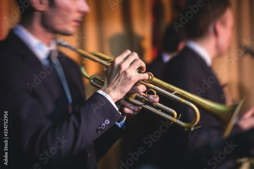 Concert view of a male trumpeter, professional trumpet player with vocalist and musical during jazz band performing music