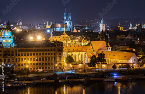 A distant view of historic buildings in Old Town from across the Vltava River at night. 