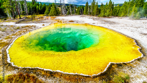 Yellow sulfur mineral deposits around the green and turquoise waters of the Morning Glory Pool in the Upper Geyser Basin along the Continental Divide Trail in Yellowstone National Park, Wyoming, USA