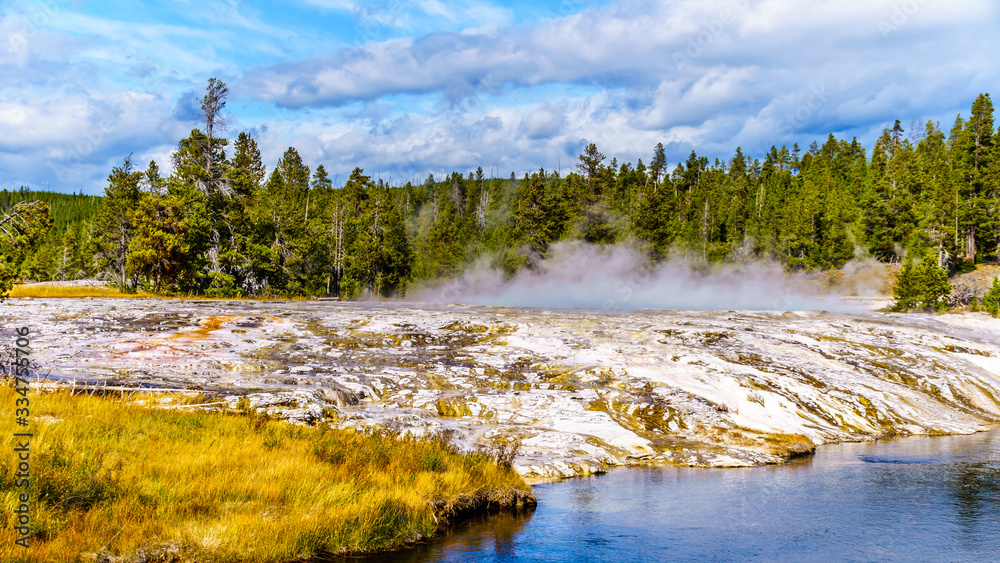 Hot water from the Oblong Geyser flowing into the Firehole River in the Upper Geyser Basin along the Continental Divide Trail in Yellowstone National Park, Wyoming, United States