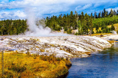 Hot water from the Oblong Geyser flowing into the Firehole River in the Upper Geyser Basin along the Continental Divide Trail in Yellowstone National Park, Wyoming, United States
