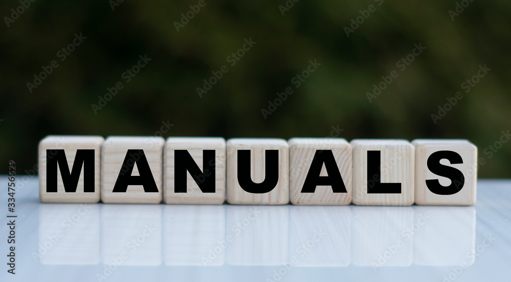 The concept of the word MANUALS on cubes on a beautiful green background