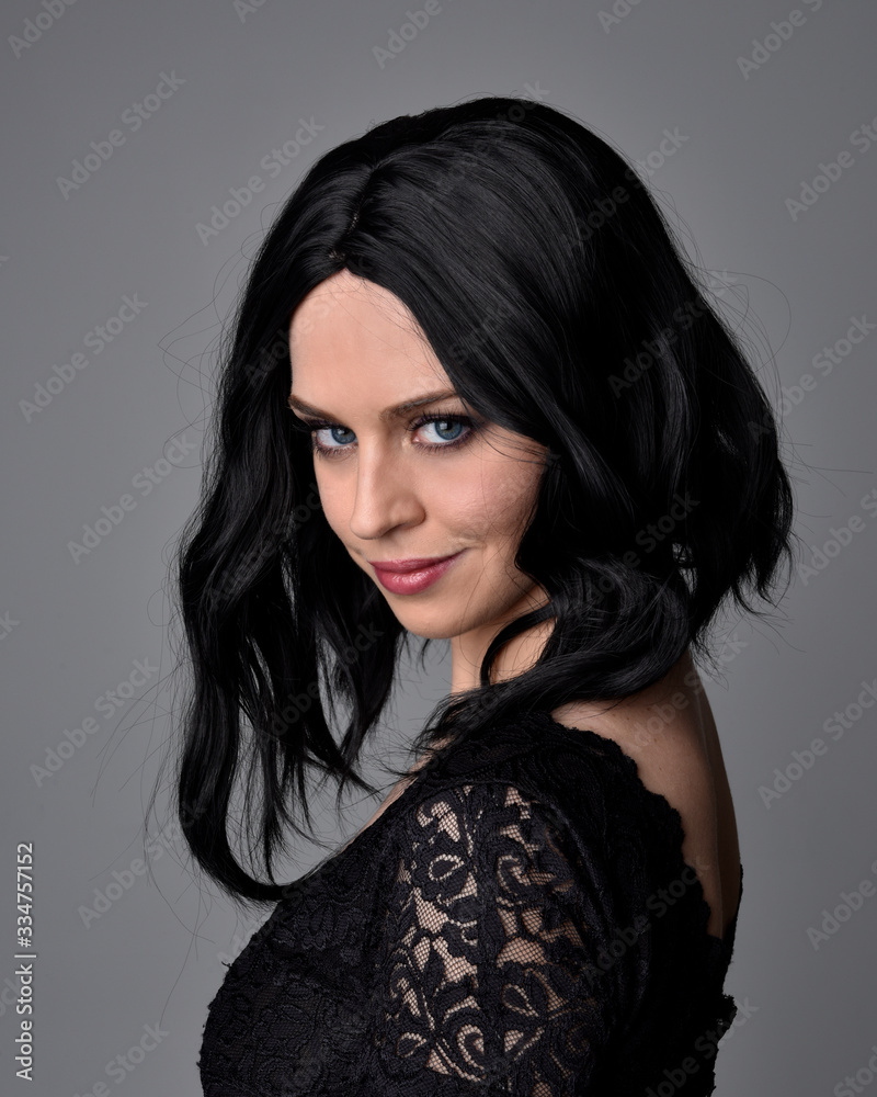 Close up portrait of a pretty, goth girl with dark hair posing in front a studio background. Close up portrait of a pretty, goth girl with dark hair posing in front a studio background.