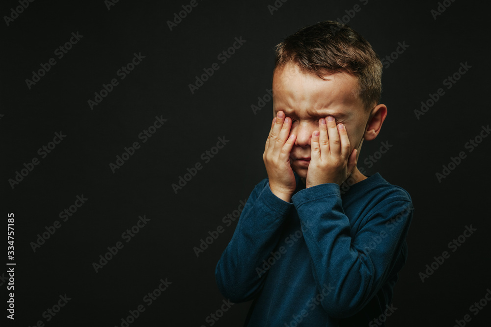 a child whose depression is on a black background with his hands closed a child whose depression is on a black background with his hands closed