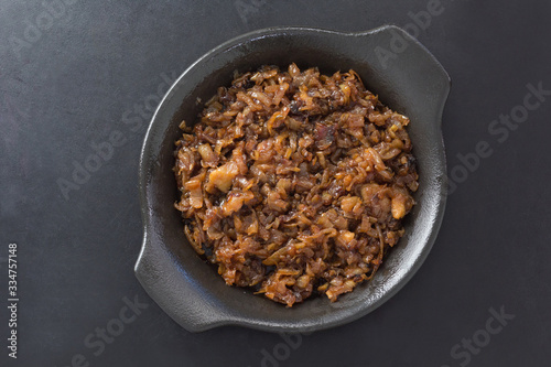 Foto Top view of caramelized onion on black plate on the black background